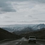 Stare auto jedzie górską drogą w Alpach pod zachmurzonym niebem