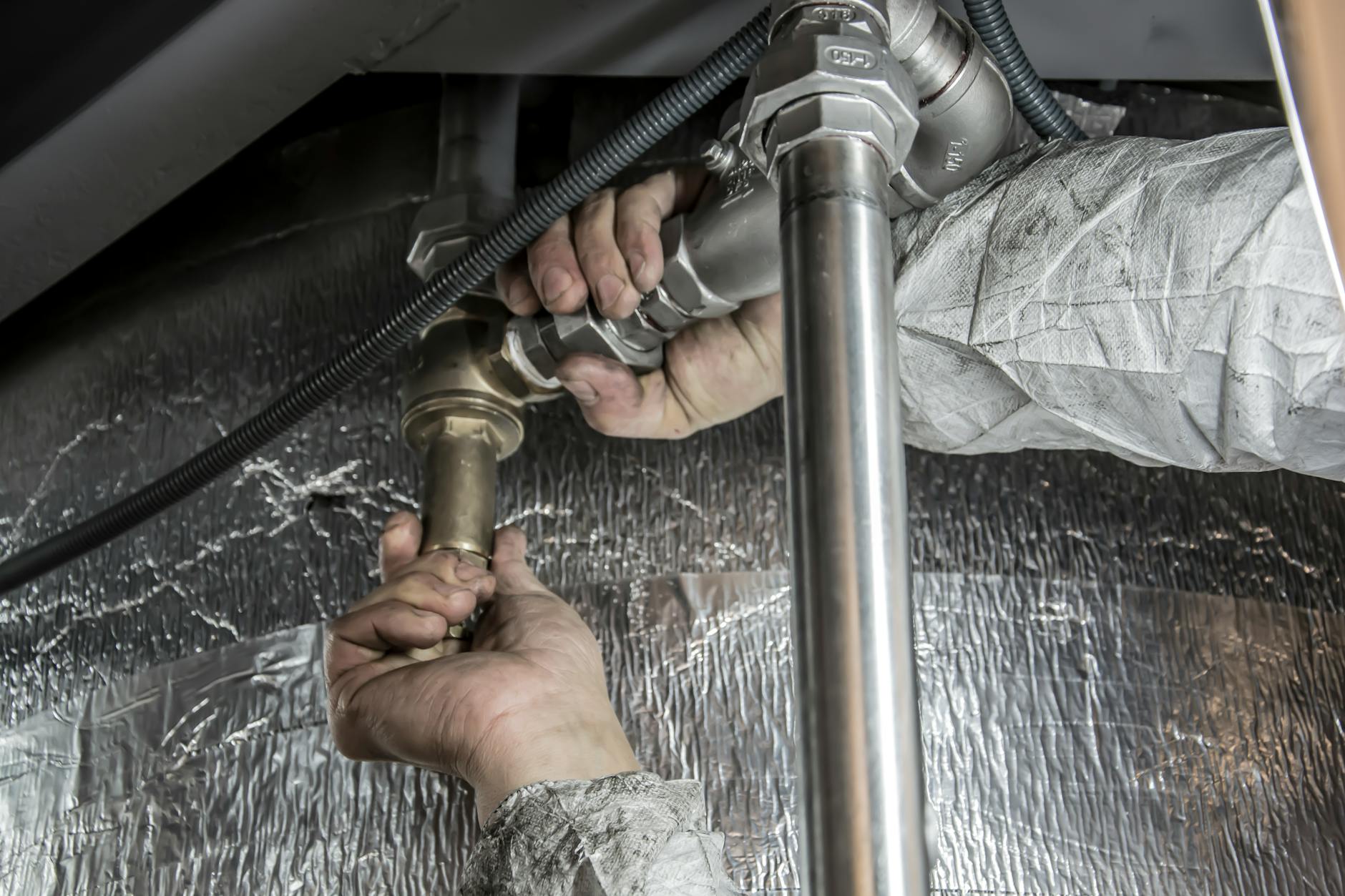 Ręce hydraulika montujące stalowe rury instalacji wodnej w domu